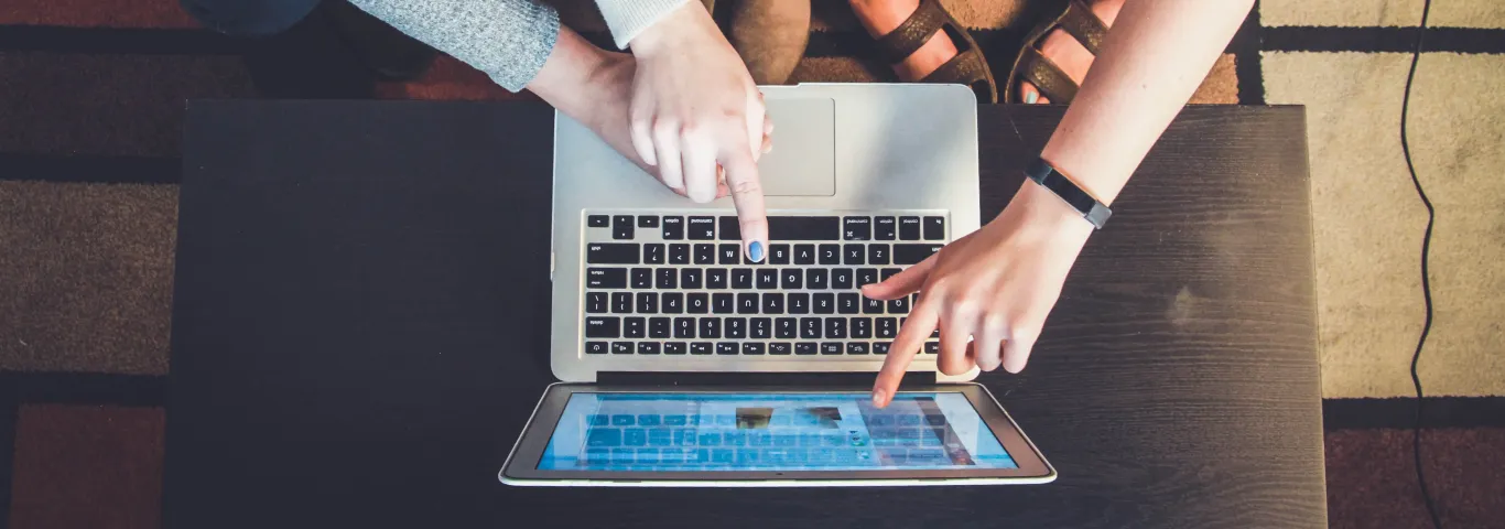 three students gesturing to the screen of a laptop