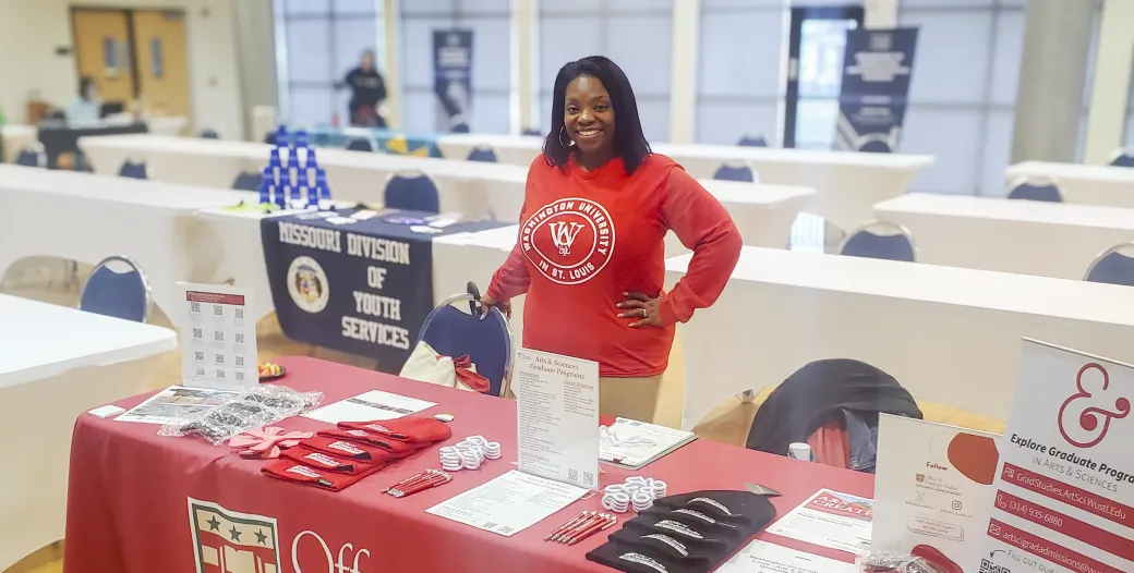 "A person standing a table at a recruiting event"