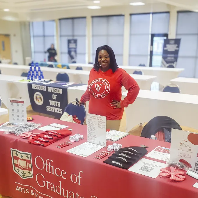 "A person standing a table at a recruiting event"